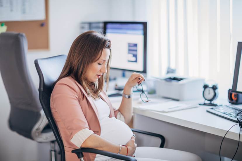 Pregnant woman holding belly at work - Pregnancy Discrimination